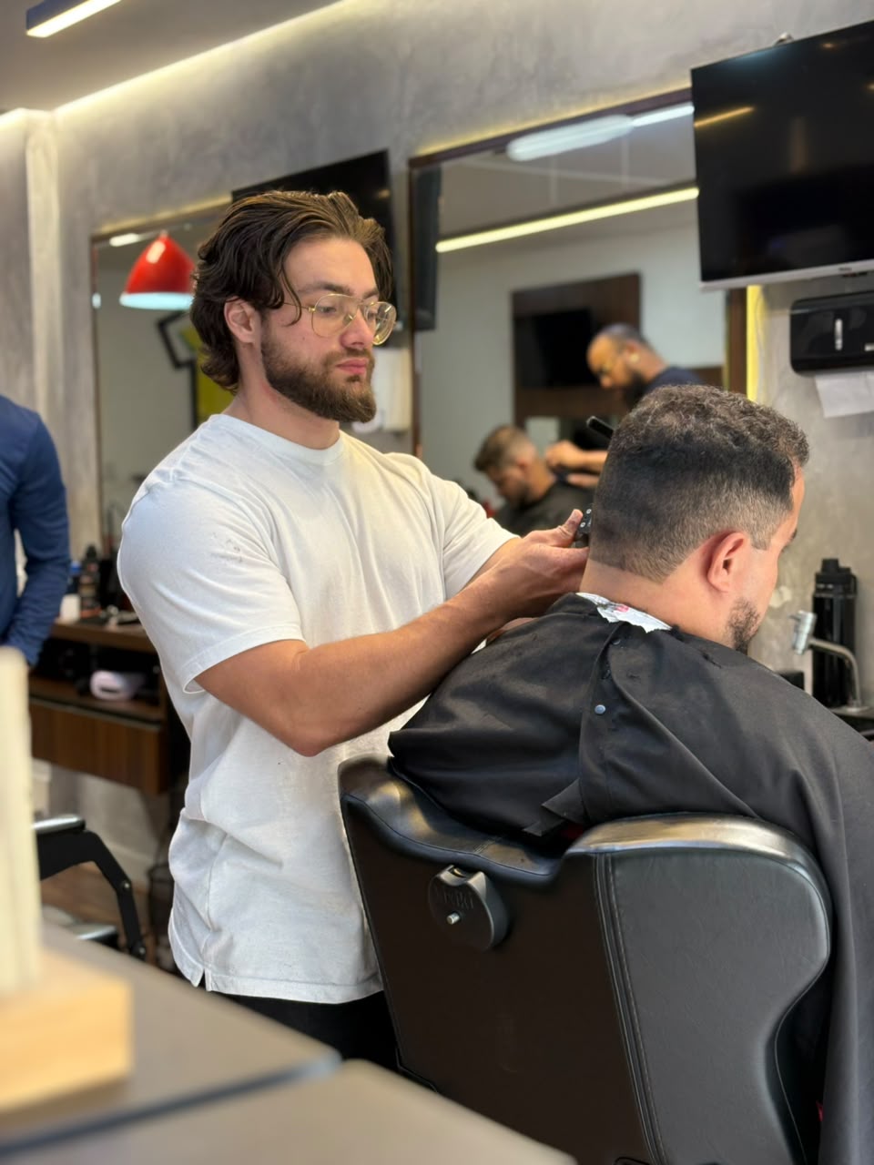Barbeiro realizando corte masculino na Confrade Barbearia