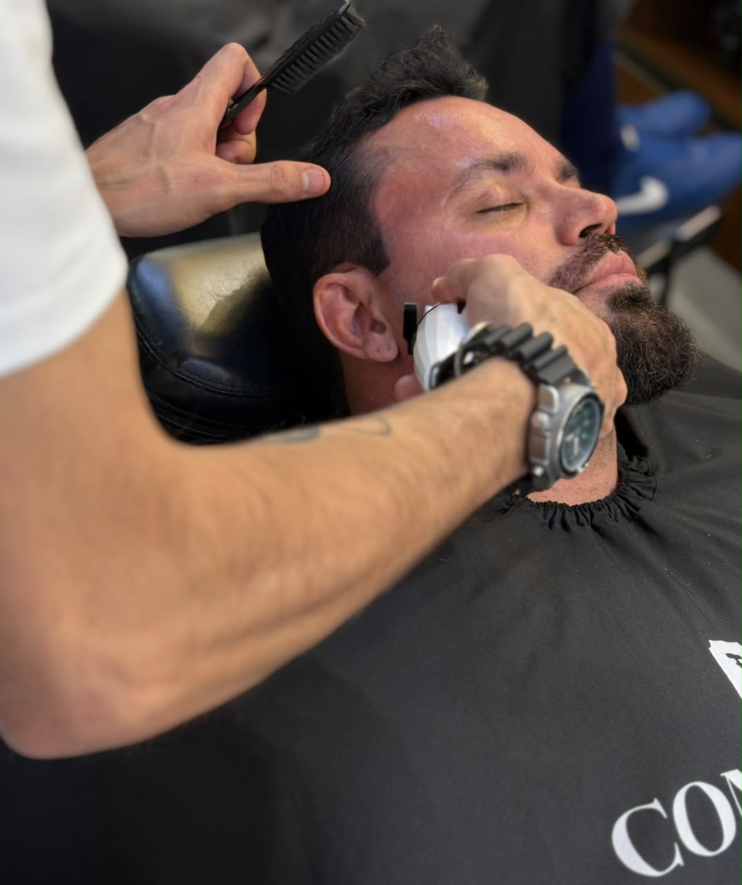 Barbeiro da Confrade finalizando a barba de um cliente com máquina